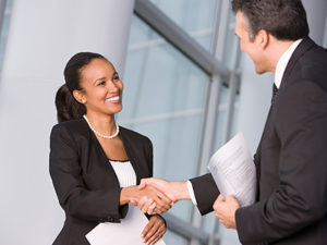 Professional female standing and shaking the hand of a professional male in the offices of The AGA Group Dental Staffing Agency