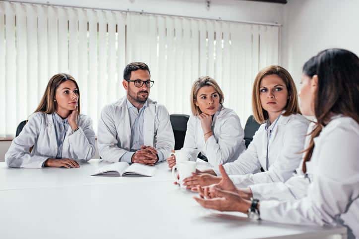 Healthcare professionals in office setting discussing hiring a practice manager and operational leadership decisions