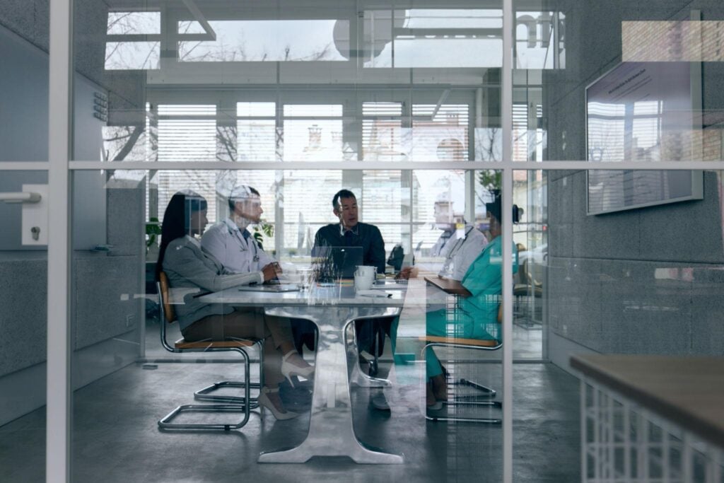 Healthcare leadership team meeting in a glass conference room to discuss a hiring decision